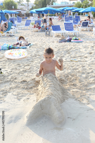 Happy boy, child play with sand in Ayia Napa, Cyprus. Makronissos Beach. Summer swim, travel. Kids in water. Active sea recreation. Coastal landscape. Mermaid-kid photo
