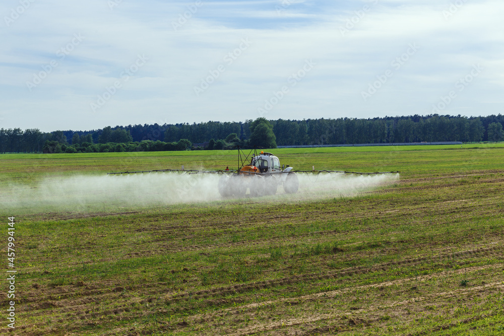 Fototapeta premium Tractor sprays liquid chemical fertilizers