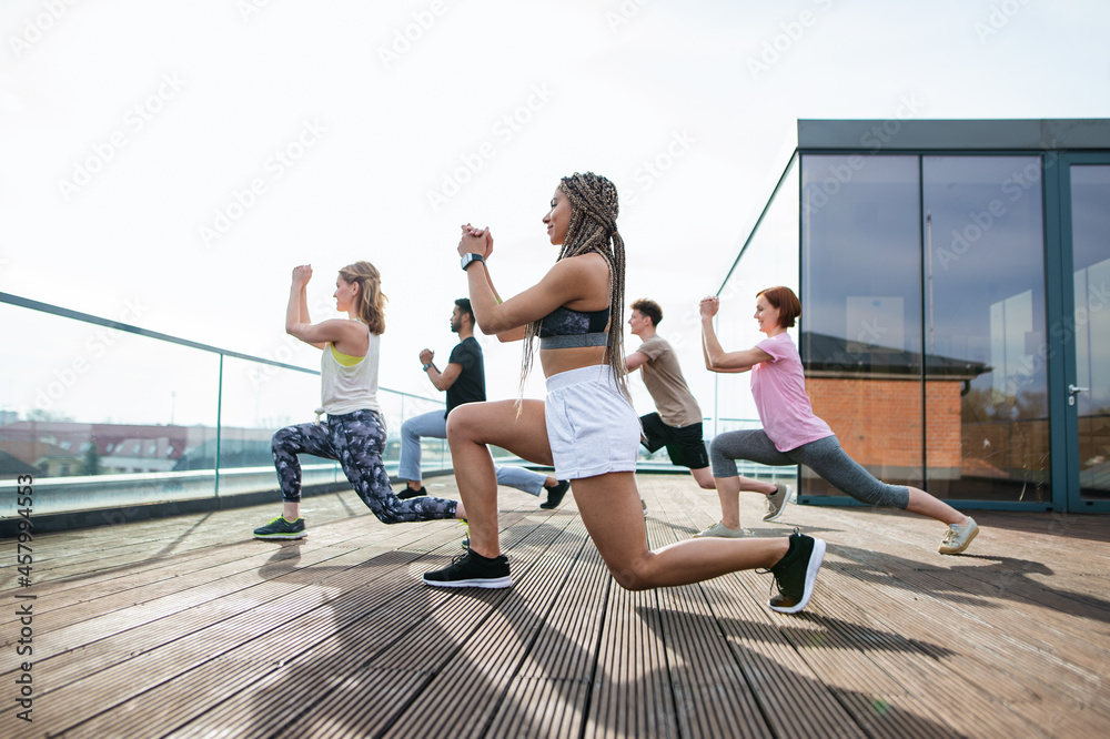 Group of young people doing exercise outdoors on terrace, sport and healthy lifestyle concept.