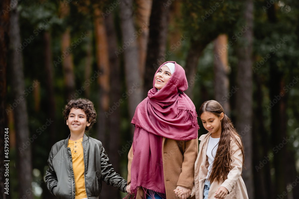 Muslim woman smiling near kids outdoors