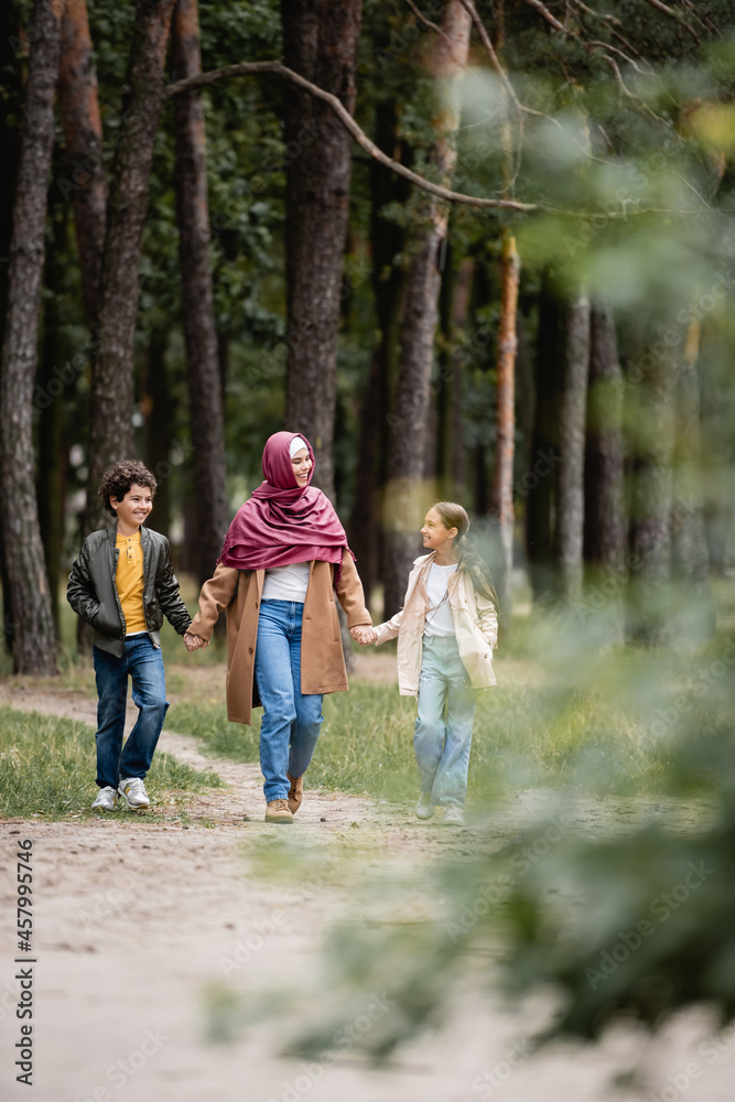 Cheerful arabian mother in hijab walking with kids in park Cheerful arabian mother in hijab walking with kids in park