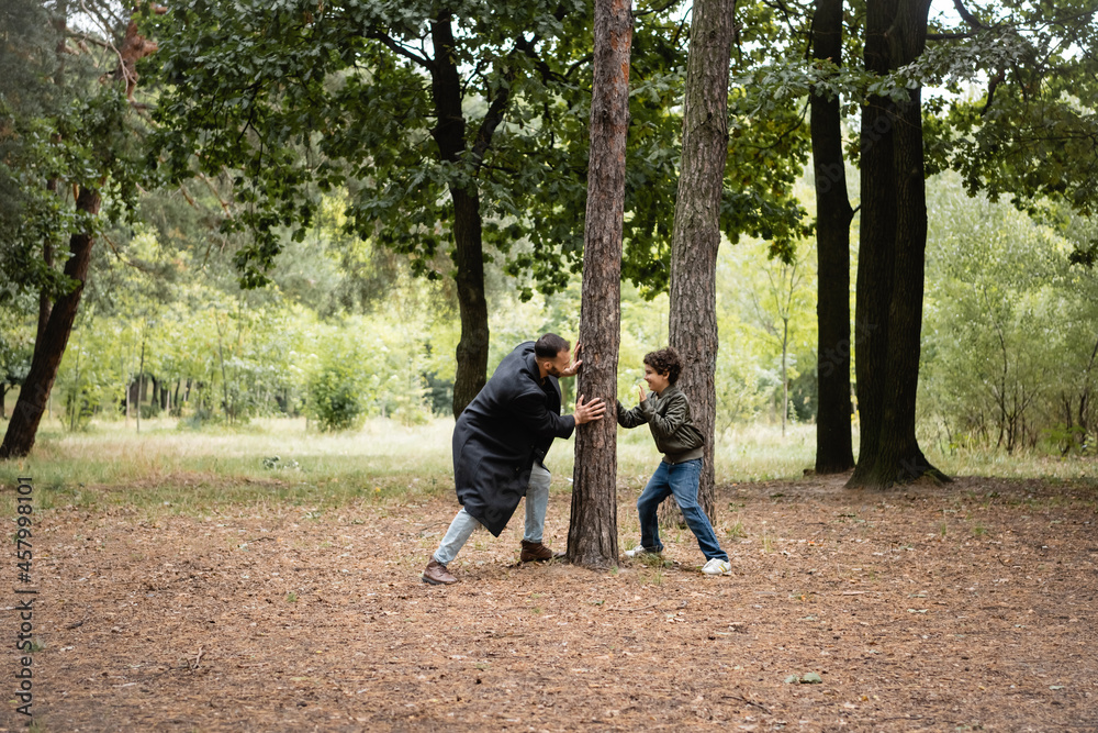 Arabian father playing with son near tree in park Arabian father playing with son near tree in park