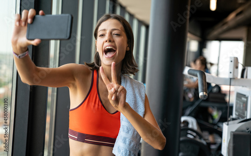Portrait of a cheerful woman using smartphone in fitness gym