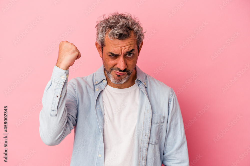 Middle age caucasian man isolated on pink background showing fist to camera, aggressive facial expression. Middle age caucasian man isolated on pink background showing fist to camera, aggressive facial expression.