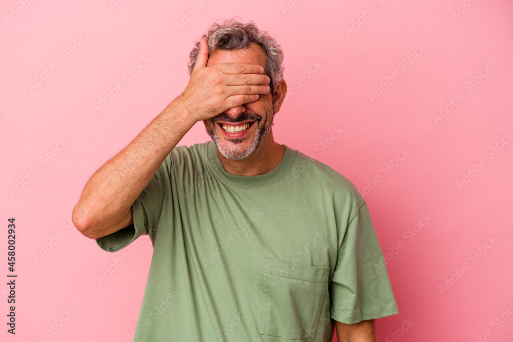 Middle age caucasian man isolated on pink background covers eyes with hands, smiles broadly waiting for a surprise. Middle age caucasian man isolated on pink background covers eyes with hands, smiles broadly waiting for a surprise.