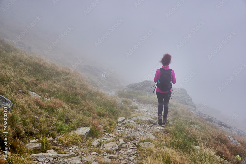 Woman hiker with backpack on a trail in the mountains