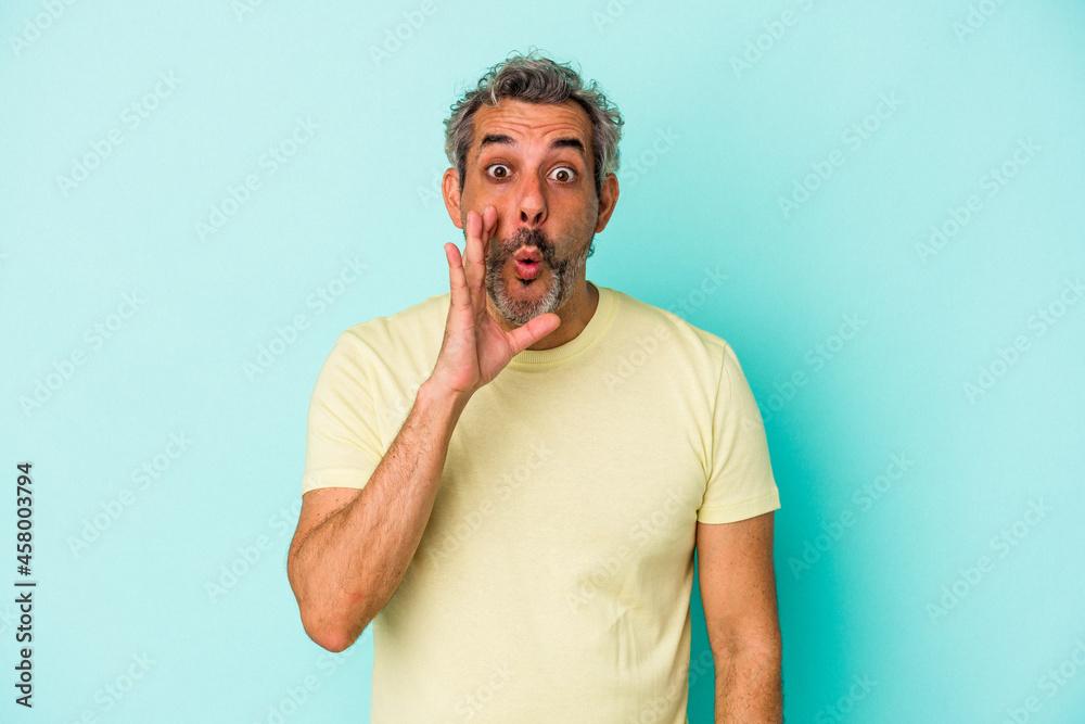 Middle age caucasian man isolated on blue background is saying a secret hot braking news and looking aside Middle age caucasian man isolated on blue background is saying a secret hot braking news and looking aside