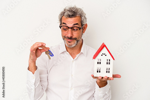 iddle age business man holding keys and toy home isolated on blue background photo