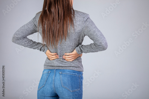 Spine osteoporosis. Scoliosis. Spinal cord problems on woman's back. Attractive female person suffers from backache. All on gray background. Painful back on female body photo