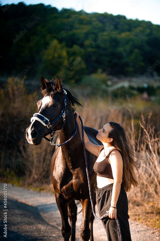 Obraz premium Young girl with horse at summer evening day, sunset light