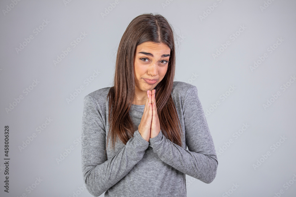 Beautiful pleased young female has broad smile, rouge cheeks, closes eyes and keeps palms together, being in anticipation of something important for her, isolated over white studio background. Beautiful pleased young female has broad smile, rouge cheeks, closes eyes and keeps palms together, being in anticipation of something important for her, isolated over white studio background.
