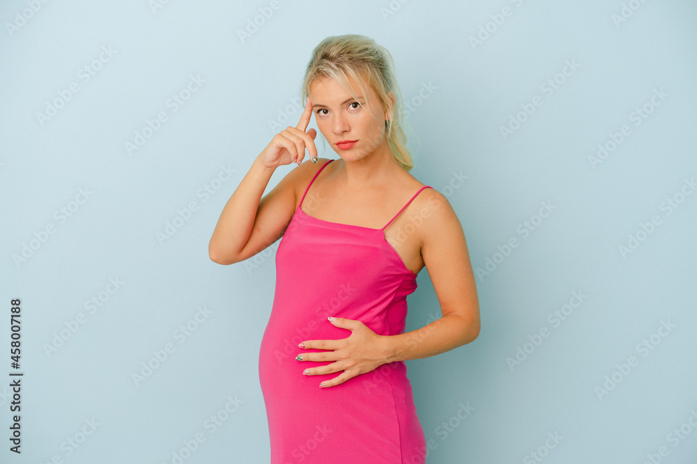 Young Russian woman pregnant isolated on blue background pointing temple with finger, thinking, focused on a task. Young Russian woman pregnant isolated on blue background pointing temple with finger, thinking, focused on a task.