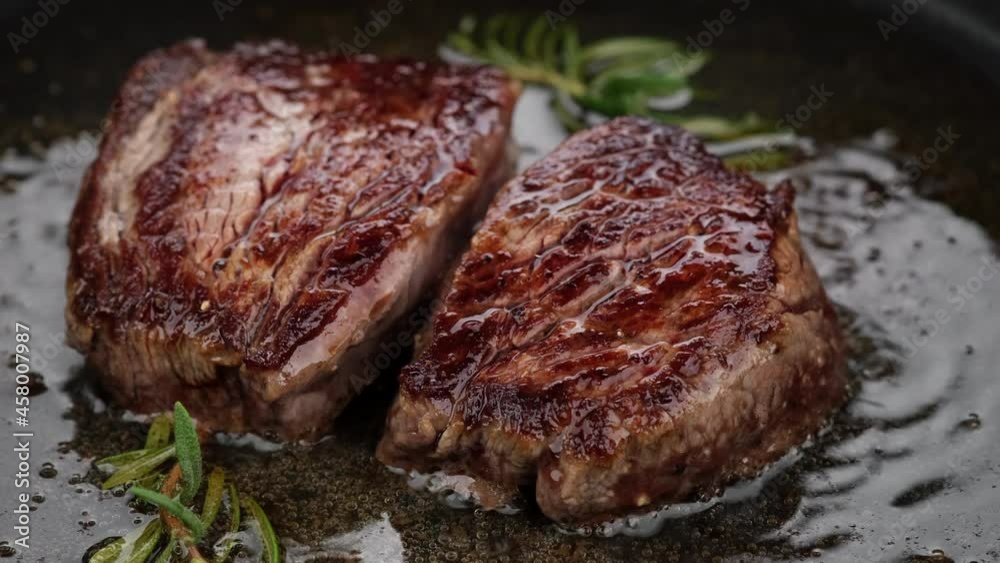 Cooking juicy meat steak with spices and herbs in pan, close up. Roasting filet mignon. 4K UHD video Cooking juicy meat steak with spices and herbs in pan, close up. Roasting filet mignon. 4K UHD video