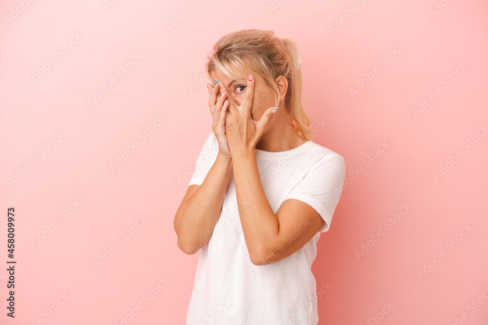 Young Russian woman isolated on pink background blink through fingers frightened and nervous. Young Russian woman isolated on pink background blink through fingers frightened and nervous.