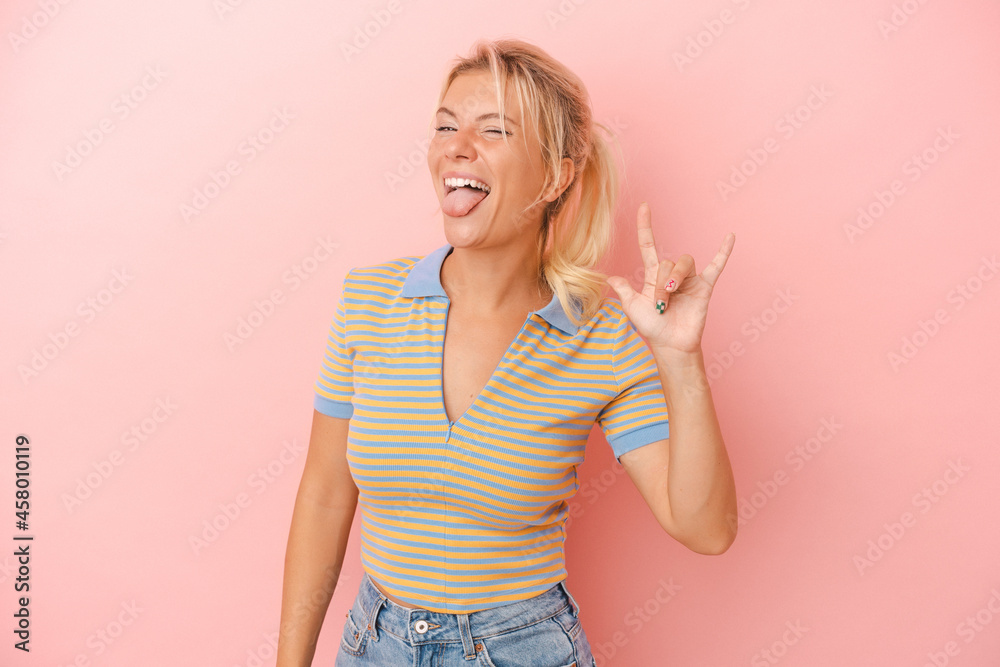 Young Russian woman isolated on pink background showing a horns gesture as a revolution concept.