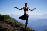 Back view of woman practicing yoga on background of evening mountains. Meditating female is balancing on one leg after sunset. Concept of meditation.