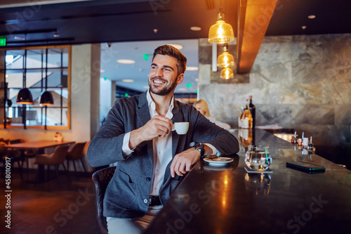 Foto The happy middle-aged man in elegant formal clothes sitting in a hotel cafe and having his afternoon coffee