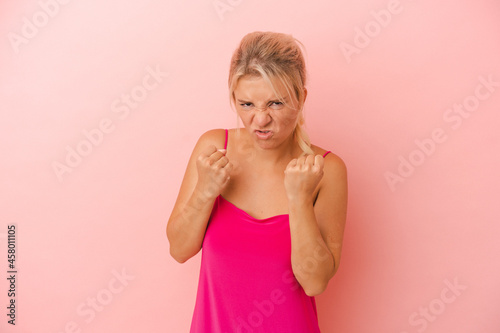 Young Russian woman isolated on pink background showing fist to camera  aggressive facial expression.