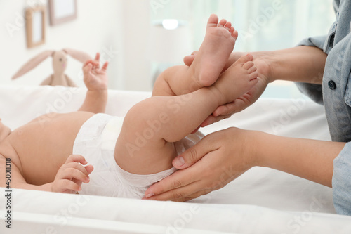 Mother changing her baby s diaper on table at home  closeup