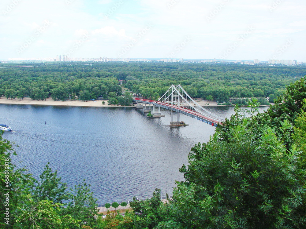Unique natural picture of the blue Dnieper surface under the red pedestrian bridge connecting Kyiv with the island. Unique natural picture of the blue Dnieper surface under the red pedestrian bridge connecting Kyiv with the island.