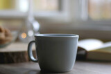 Bowl of cookies, cup of hot beverage, open book and lit candles on a table. Selective focus.