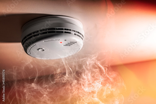 Smoke detector and interlinked fire alarm in action background photo