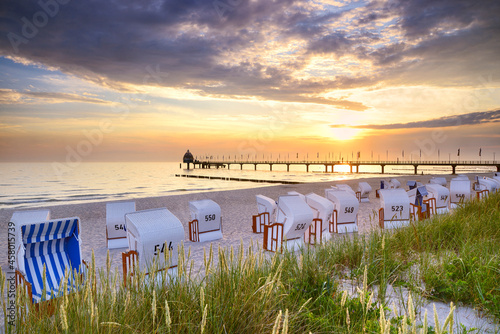 Zingst, Halbinsel Fischland-Darß-Zingst, Mecklenburg-Vorpommern, Germany -.View towards Seebrücke Zingst from Zingst beach with roofed chair and grass on sand dunes in the foreground. photo