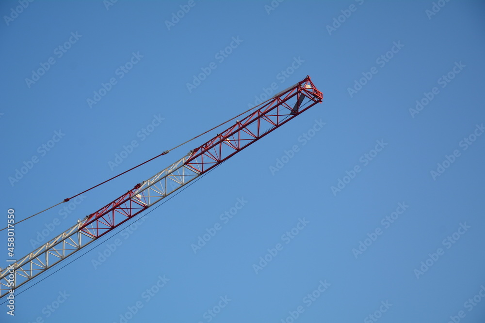 The crane jibs against blue sky. Construction site. The crane jibs against blue sky. Construction site.