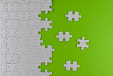 Unfinished white puzzle pieces on a green background