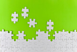 Unfinished white puzzle pieces on a green background