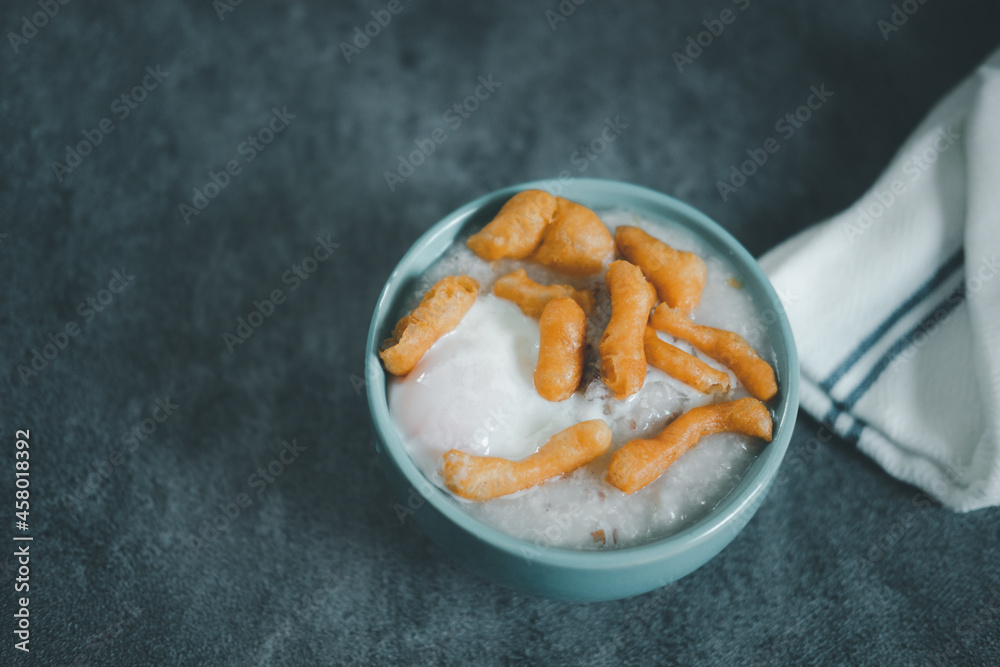 Fototapeta premium Thai porridge rice gruel in bowl congee with soft-boiled egg and deep-fried dough stick topping
