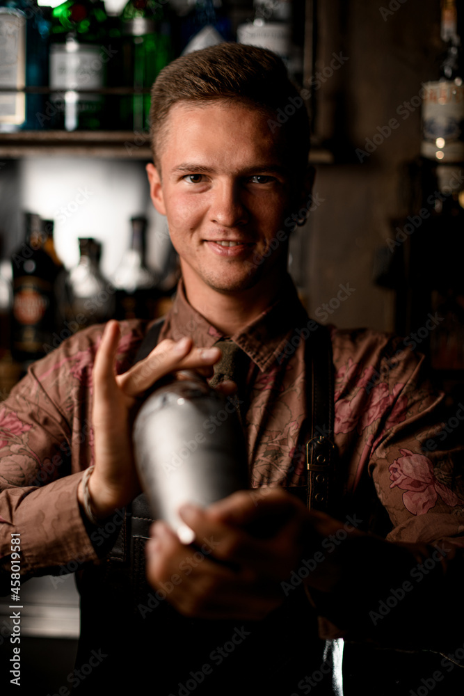 portrait of smiling man bartender holds a shaker in his hands and shakes it