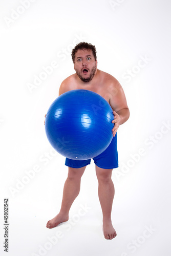 Funny fat man training with a fitness ball. Adult guy on a white background. Copy space. Active sports with a diet. 