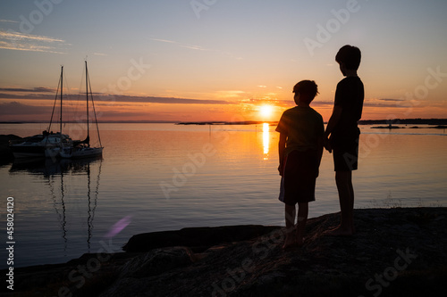 Kids looking out over the sunset during a calm evening at Lyngholmen outside Fredrikstad in Norway during summer. © ThomasRuss