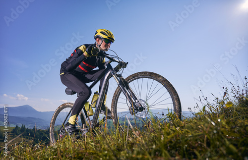 Fotografia Young man cycling uphill on sunny day with blue sky on background