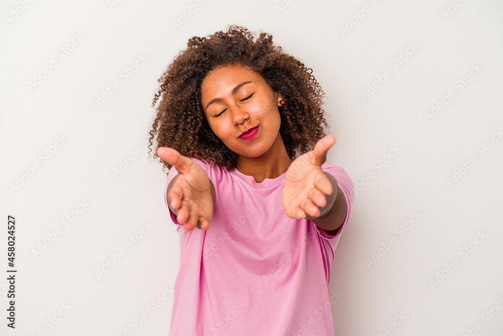 Young african american woman with curly hair isolated on white background folding lips and holding palms to send air kiss. Young african american woman with curly hair isolated on white background folding lips and holding palms to send air kiss.