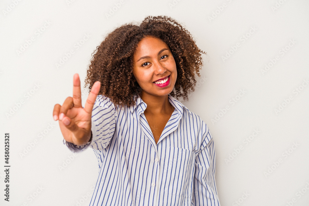 Young african american woman with curly hair isolated on white background joyful and carefree showing a peace symbol with fingers. Young african american woman with curly hair isolated on white background joyful and carefree showing a peace symbol with fingers.
