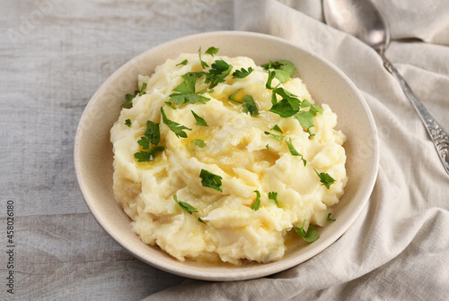 A plate of mashed potatoes poured with melted butter and seasoned with greens