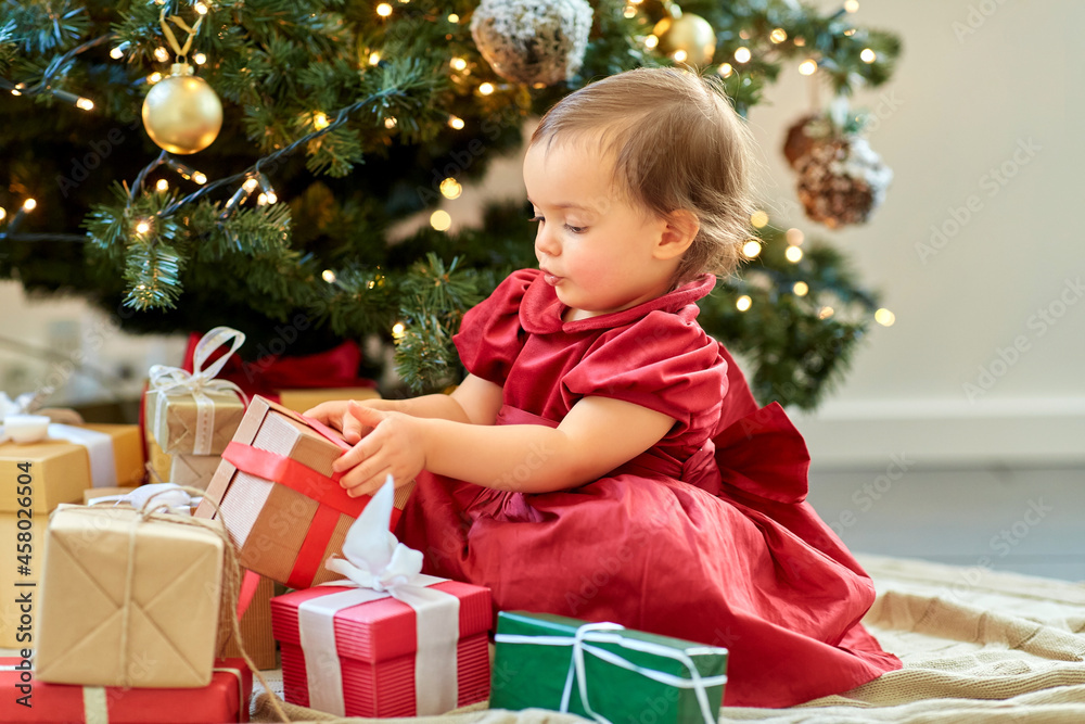christmas, holidays and childhood concept - happy baby girl opening gifts at home christmas, holidays and childhood concept - happy baby girl opening gifts at home