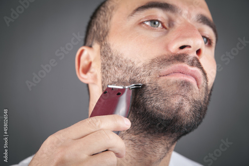 Caucasian man shaving with electric trimmer.