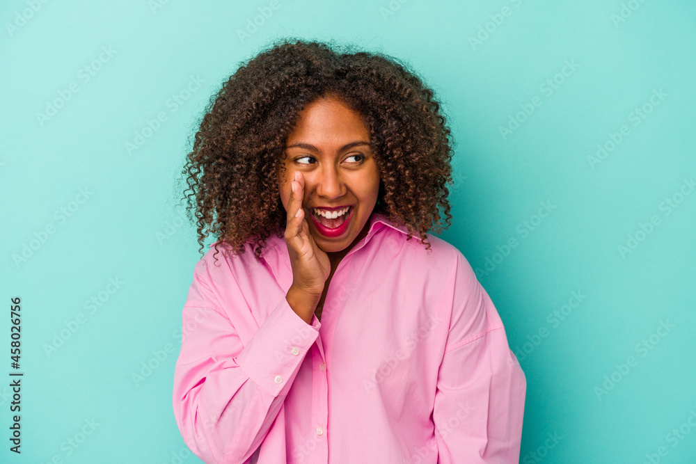 Fototapeta premium Young african american woman with curly hair isolated on blue background shouting excited to front.