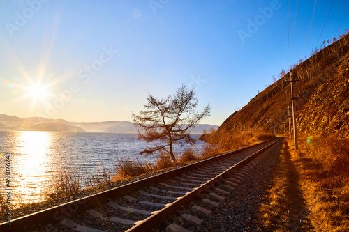 Circum Baikal railway running along the shore of Lake Baikal on an autumn sunny day with a yellow landscape around