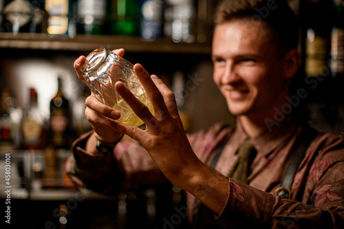 Selective focus of crystal shaker with cocktail in male hands.
