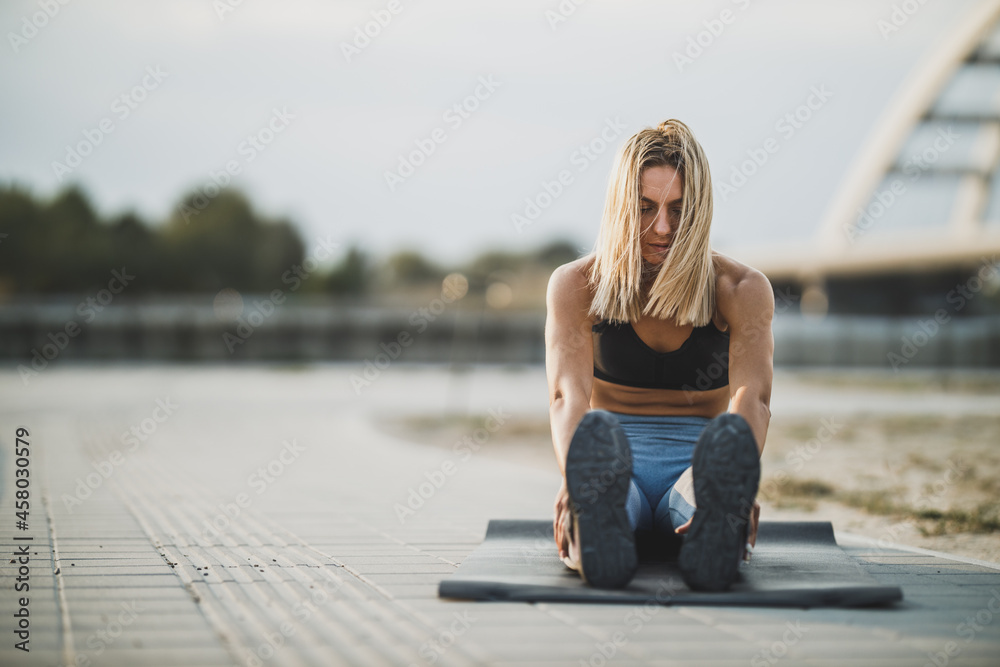 Female Athlete Doing Stretching Exercises And Warming Up Before Outdoors Training