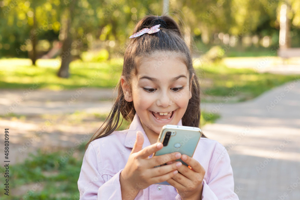 Happy child girl with phone outdoors. Gagets consept Happy child girl with phone outdoors. Gagets consept