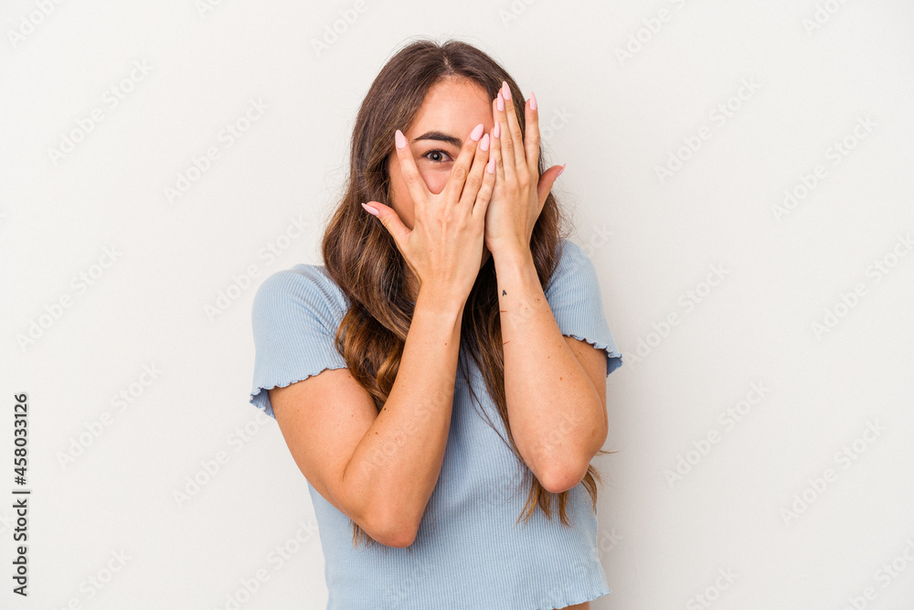 Young caucasian woman isolated on white background blink through fingers frightened and nervous. Young caucasian woman isolated on white background blink through fingers frightened and nervous.