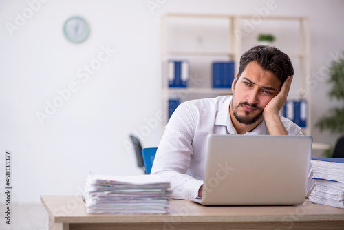 Young male employee unhappy with excessive work in the office