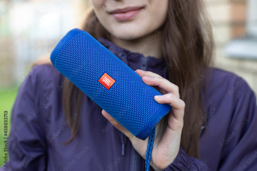 Minsk, Belarus - 12 July 2021. Young woman smiling and holding in hand blue  JBL Flip 4 portable Bluetooth speaker outdoor Stock Photo | Adobe Stock