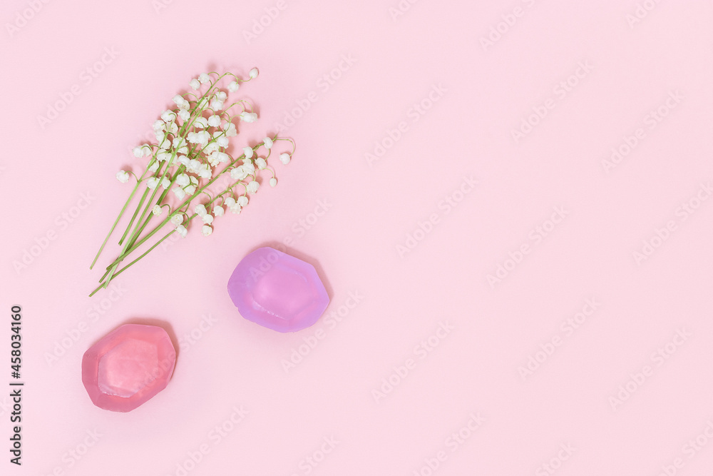 Flowers of lilies of the valley and fragrant soap on soft pink background with free space for text. Handmade soap bars. Aromatherapy, beauty spa background. Top view.