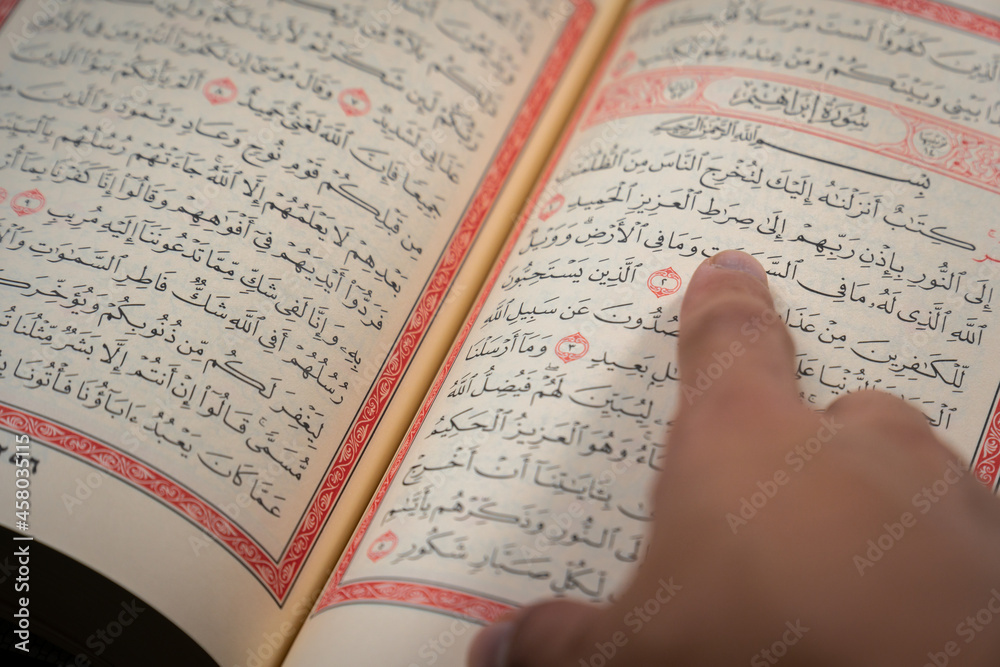 Quran (Koran) - close up of holy book of Muslims, with hand pointing ...